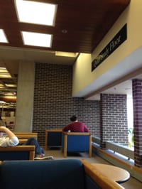Two people study near windows at the Uconn Library.
