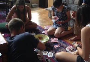 5 young adults lounge on the floor to sort playing cards
